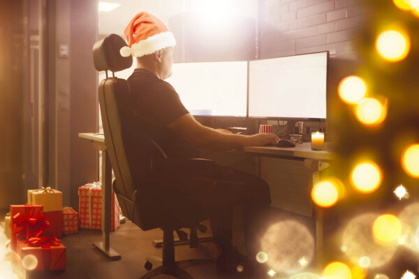 Mies tietokoneen ääressä, kuvassa joulukoristeita